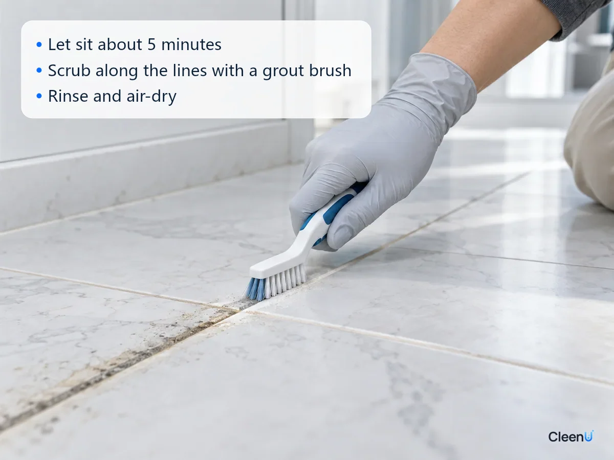 AI illustration: A gloved hand scrubbing tile grout with a narrow brush, the scrubbed section back to a light color