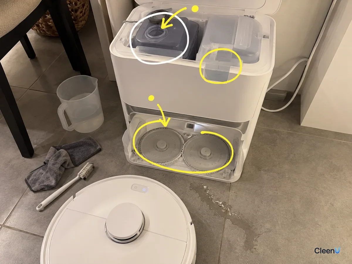 An open white dock with the solution compartment, clean water tank, its fill area and the mop wash tray marked for refilling.