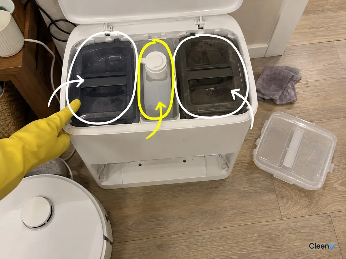 An open robot mop dock with its clean water tank, solution bottle slot and dirty water tank marked, showing where each one goes.