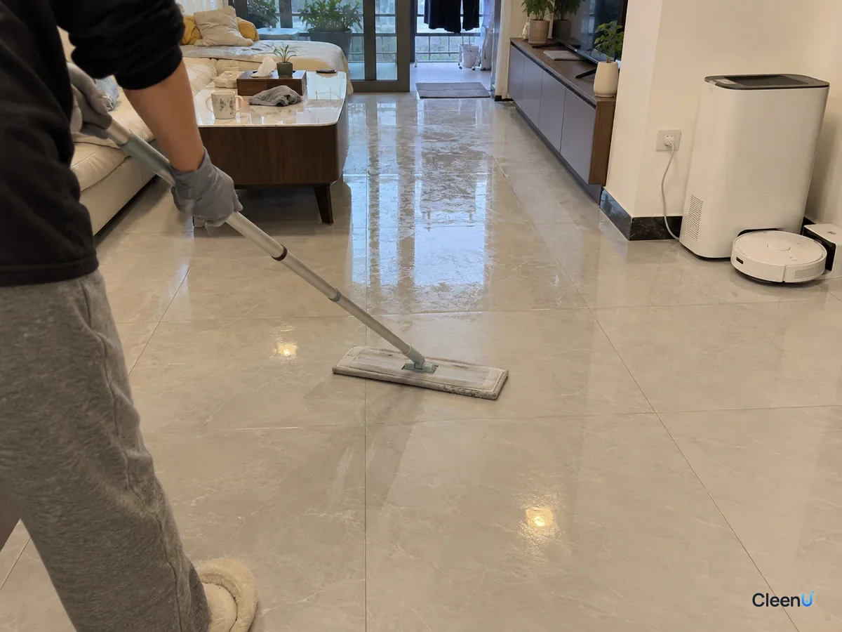 Same living room later: the flat mop with a fresh dry pad following right behind a damp-mopped strip, the wiped lane dull and dry, a wet sheen still ahead