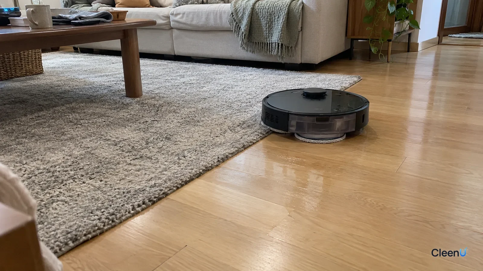 AI illustration: A light gray low-pile rug in the middle of a light wood living room floor, with a robot mop working the wood along the rug's edge