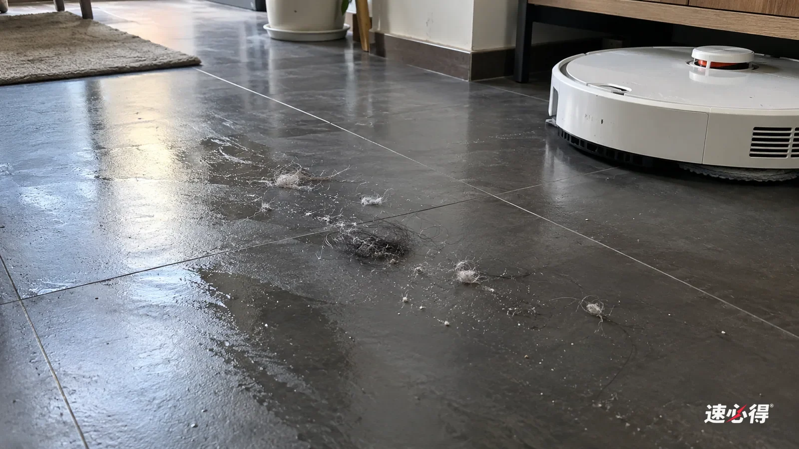 AI 示意图：侧光下的深色瓷砖地面上，扫地机器人拖过的路线上散落着细小的白色毛絮和几小团湿的头发纤维，旁边是停着的白色扫拖机器人