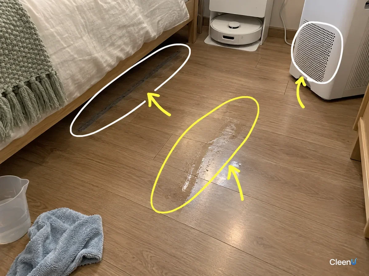 A bedroom floor after robot mopping with a damp streak, dust under the bed edge and the air purifier marked as allergy hot spots.