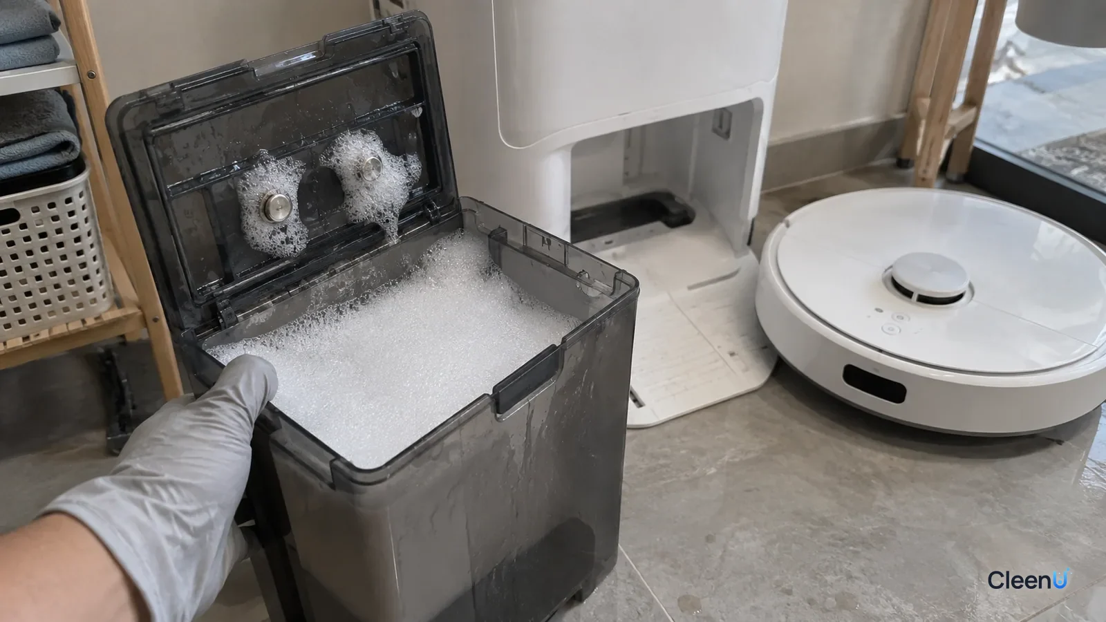 AI illustration: A dirty water tank pulled from a white self-cleaning dock and piled with white foam, the two metal contacts inside the lid buried in bubbles